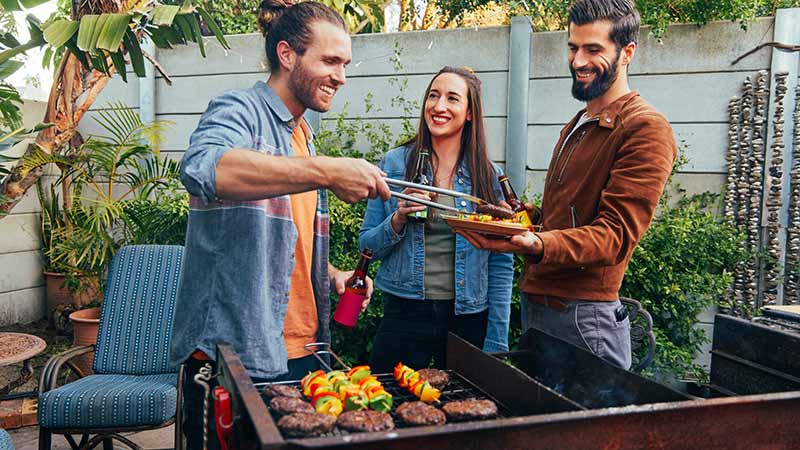 groep vrienden staat samen rondom een bbq
